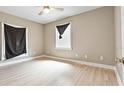 Neutral bedroom with light wood floors, ceiling fan, and window with dark coverings at 5004 E Seneca Ave, Tampa, FL 33617