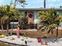 Charming home featuring beautiful landscaping, a decorative pink door, and lush tropical palm trees at 70 Virginia Ct, Englewood, FL 34223