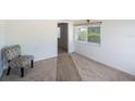 Bright bedroom featuring neutral carpeting, white walls, and a patterned accent chair near a sunlit window at 4100 46Th N Ave, St Petersburg, FL 33714
