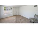 The bedroom features neutral carpeting, a large window with blinds, white walls, and a decorative chair at 4100 46Th N Ave, St Petersburg, FL 33714