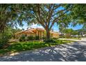 Charming home with lush landscaping and a large tree providing ample shade on a sunny day at 8202 Shadow Pine Way, Sarasota, FL 34238