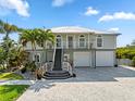 Charming two-story home with a well-maintained driveway, stairs to the front door, and tropical landscaping at 24145 Blackbeard Blvd, Punta Gorda, FL 33955