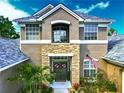 Charming home with stone accents, double doors, and lush landscaping surrounding the entrance at 3008 Sutton Woods Dr, Plant City, FL 33566