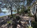 Scenic backyard featuring a brick patio overlooking a tranquil lake view surrounded by mature trees at 560 7Th S St, Safety Harbor, FL 34695