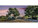 Inviting blue single-story home at dusk, complete with carport and mature landscaping in a tranquil setting at 6801 16Th N St, St Petersburg, FL 33702