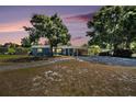 Inviting blue single-story home at dusk, complete with carport and mature landscaping in a tranquil setting at 6801 16Th N St, St Petersburg, FL 33702