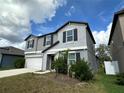 Two-story home featuring a two-car garage, dark shutters, and manicured front lawn at 13344 Great Plains S Dr, Riverview, FL 33579