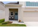 Close up of the front of the home featuring a blue door, covered porch, and two-car garage at 34327 Verbena St, Wesley Chapel, FL 33545