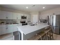 Open kitchen with large island, stainless steel appliances, and light gray cabinets at 34327 Verbena St, Wesley Chapel, FL 33545