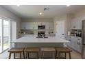 Modern kitchen with island, seating, stainless steel appliances, and light gray cabinets at 34327 Verbena St, Wesley Chapel, FL 33545