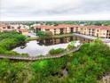 Aerial view of the buildings with serene pond and lush landscape and wooden walkway at 4333 Bayside Village Dr # 310, Tampa, FL 33615