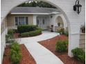 Inviting home entrance featuring an arched entryway and a beautifully landscaped yard with decorative statues at 7026 Lenape Cir, New Port Richey, FL 34653