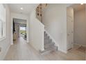 Bright foyer with tile flooring, a staircase with carpeted steps, and neutral walls, creating an open and welcoming entrance at 16231 Pine Mist Dr, Bradenton, FL 34211