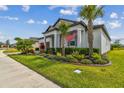 Stylish home with lush landscaping, palm trees, and an American flag displayed prominently in the front yard at 31840 Magna Gulf Loop, San Antonio, FL 33576