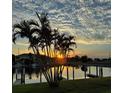 Sunset view over the community waterway with dock and palm trees at 3221 White Ibis Ct # C1, Punta Gorda, FL 33950