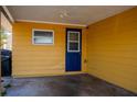 Covered carport area featuring a blue entry door, side window, and ample parking space at 2616 Bayshore Gardens Pkwy, Bradenton, FL 34207