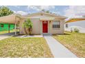 Charming single-story home featuring a red front door, covered parking, and drought resistant landscaping at 4812 N 37Th St, Tampa, FL 33610
