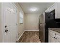 Compact kitchen with white cabinets, stainless appliances, and wood-look flooring, next to a door at 4812 N 37Th St, Tampa, FL 33610