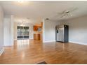 Open concept living room with hardwood floors, a ceiling fan, and stainless steel refrigerator at 408 Eunice Dr, Plant City, FL 33563