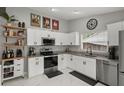 Bright kitchen with white cabinets, granite countertops, stainless steel appliances, and sleek marble floors at 4605 Steel Dust Ln, Lutz, FL 33559