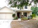 Charming two-story home with a covered front porch surrounded by landscaped flower beds at 11511 Misty Isle Ln, Riverview, FL 33579