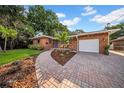 Inviting brick home with a landscaped front yard, brick driveway, and a two-car garage at 307 N Glen Ave, Tampa, FL 33609