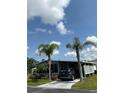 Exterior view featuring a carport and a blue car, palm trees, and landscaping on a sunny day at 5258 Wisteria Cir, New Port Richey, FL 34653