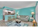 Bright living room with turquoise walls, bar seating to kitchen, and coastal-themed decor at 680 71St Ave # 9, St Pete Beach, FL 33706