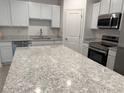 Bright kitchen featuring a large island with granite countertops and stainless appliances at 32122 Eastern Redbud Br, San Antonio, FL 33576