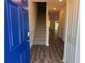 Bright entryway featuring a vibrant blue front door, wood-look floors, and a staircase at 32128 Eastern Redbud Br, San Antonio, FL 33576