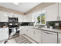 Modern kitchen featuring white cabinets, stainless steel appliances, and a window with a pleasant view at 5511 1St Avenue Nw Dr, Bradenton, FL 34209