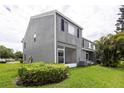 The back of the grey townhouse features a screened in porch, well-kept green lawn, and healthy hedges at 232 Countryside Key Blvd, Oldsmar, FL 34677