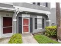 Close-up of the red front door of the townhouse with black shutters and a well-manicured lawn at 232 Countryside Key Blvd, Oldsmar, FL 34677
