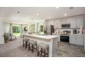 Bright kitchen featuring a center island, sleek appliances, and stylish countertops with an adjacent living area at 16408 Courlan Rd, Weeki Wachee, FL 34614