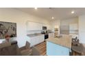 Bright kitchen featuring white cabinets, granite countertops, stainless steel appliances, island with bar seating and hardwood floors at 14684 Italy Ave, Dade City, FL 33523