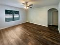 Spacious living room featuring wood-look flooring, a ceiling fan, and a bright window at 5383 Magdalene Way, Zephyrhills, FL 33541