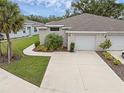 A well-maintained home featuring a two-car garage, concrete driveway, and tropical landscaping at 146 51St Street E Cir, Palmetto, FL 34221
