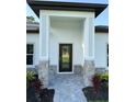 Close-up of a modern home's front door with stone accents and fresh landscaping at 1160 Edinburgh St, North Port, FL 34288
