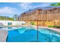 Sparkling swimming pool with a charming tiki umbrella, providing a tranquil outdoor retreat at 9497 122Nd Way, Seminole, FL 33772