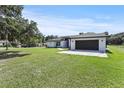 Side view of white single-story home with a dark gray two-car garage and green lawn at 1438 Mclin Dr, Plant City, FL 33565