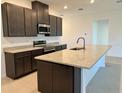 Modern kitchen features dark cabinetry, granite countertops, stainless steel appliances, and a spacious island at 27206 Adams St, Punta Gorda, FL 33983