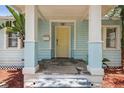 Inviting front porch with stone flooring, light blue pillars and light yellow door at 6503 N Wellington Ave, Tampa, FL 33604