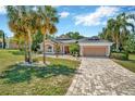 Charming home featuring a manicured lawn, mature trees, and a paved driveway leading to a two-car garage at 14680 Linden Dr, Spring Hill, FL 34609