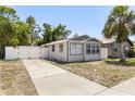 A single story grey home with a large driveway and white fence at 1465 Pierce St, Clearwater, FL 33755