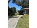 Long driveway leading to a one-car garage, with ample space for parking and a green lawn at 1317 W Alicia Ave, Tampa, FL 33604