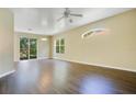 Spacious living room with dark wood floors, ceiling fan, large windows, and sliding glass door at 212 Citrus Landing Dr, Plant City, FL 33563
