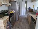 A functional kitchen with stainless steel appliances, laminate countertops, wood cabinets, and a vinyl floor at 3607 Johnson Ct, Palm Harbor, FL 34684