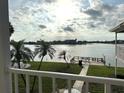 Balcony view overlooking a tranquil waterfront with lush green lawn and palm trees at 129 104Th Ave # 205, Treasure Island, FL 33706