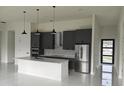 Modern kitchen boasts gray cabinets, stainless appliances, and a central island under elegant pendant lighting at 267 Santa Marta St, Port Charlotte, FL 33954