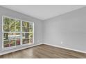 Bright, empty bedroom with a large window offering plenty of natural light, and wood-look flooring at 7511 Savannah Ln, Tampa, FL 33637